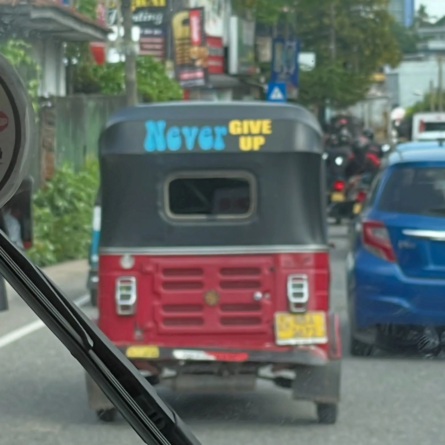 A tuk-tuk with Never Give Up painted on the back
