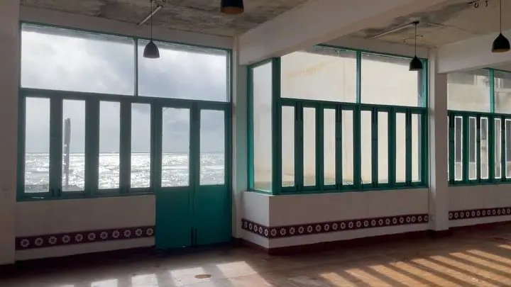 The empty gallery floor lined with teal windows